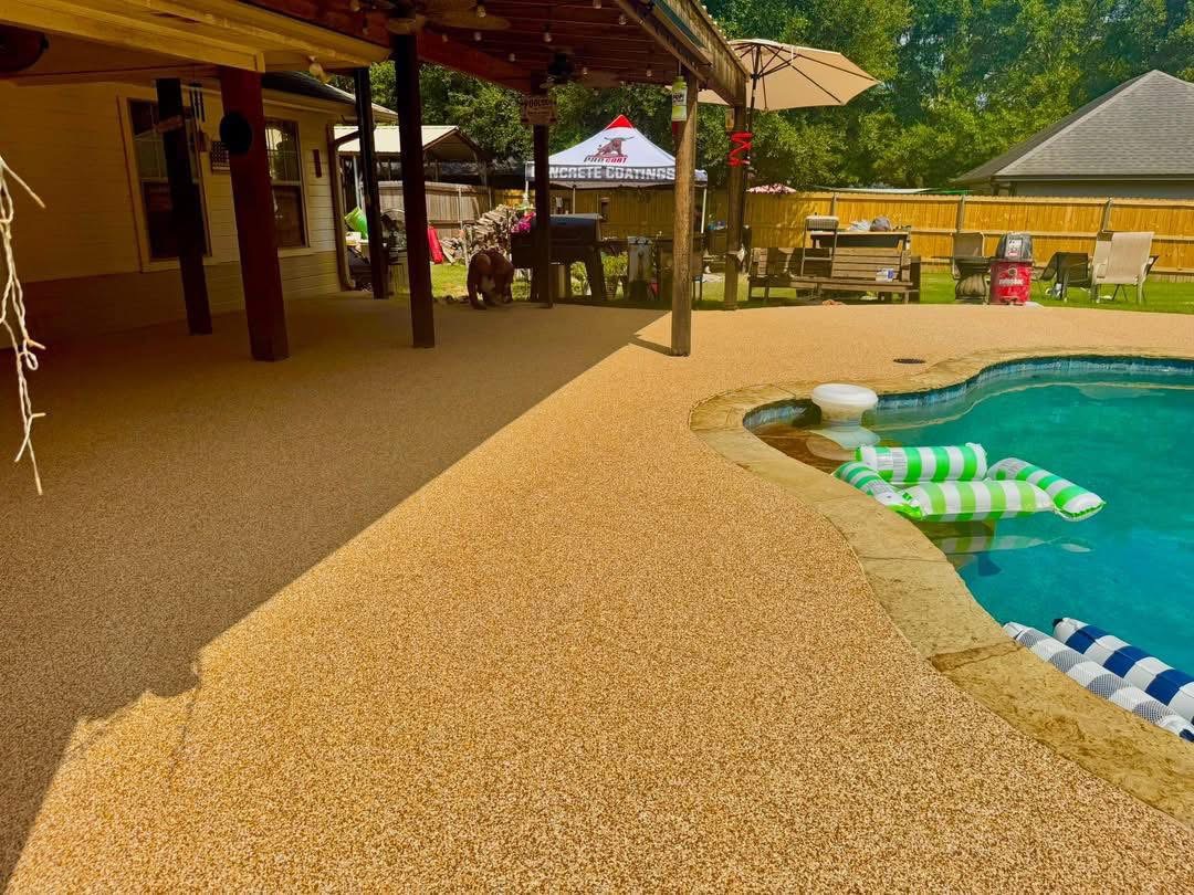 Covered patio with tan speckled rubber surfacing next to a pool with striped floats